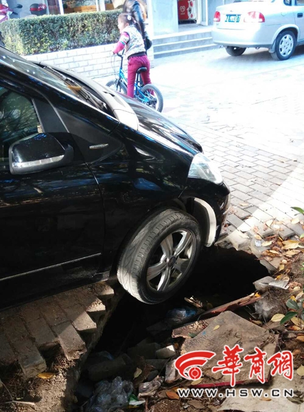 人行道上小坑“咬”住车轮 3人合力拖车