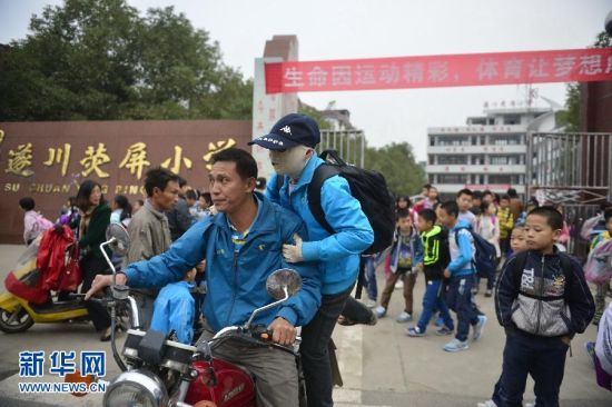 图为放学后,周涛坐着爸爸的摩托车回家。