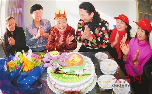 社区的工作人员(右)带着蛋糕和鲜花给老人祝寿。