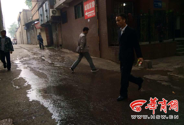 环卫工用水管冲洗垃圾台 污水顺斜坡流一路